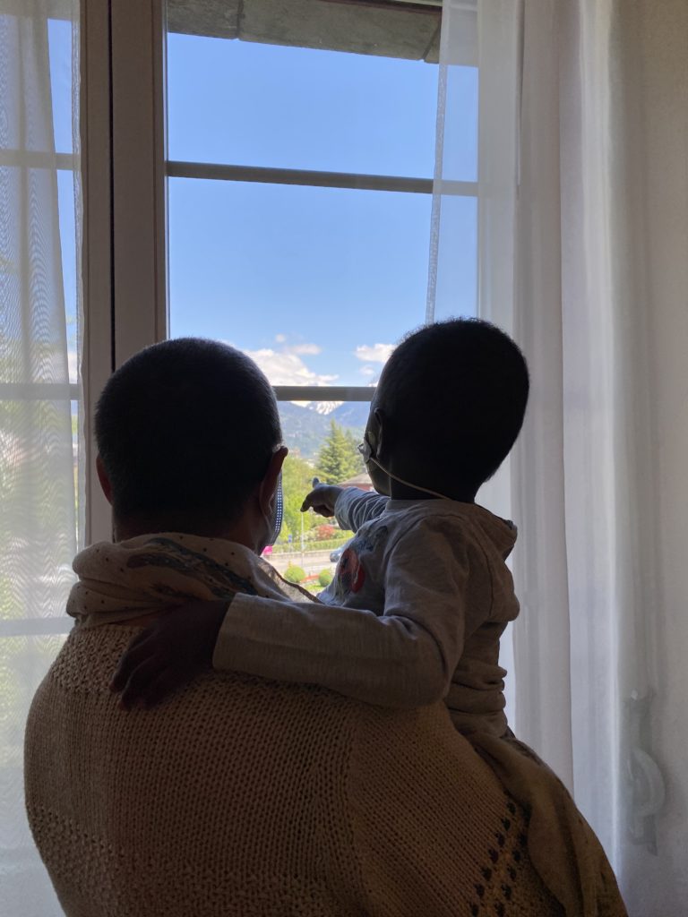 Convoyages d'enfants. Dans les bras de Marie, convoyeuse bénévole, Ibrahima patiente en salle d'attente