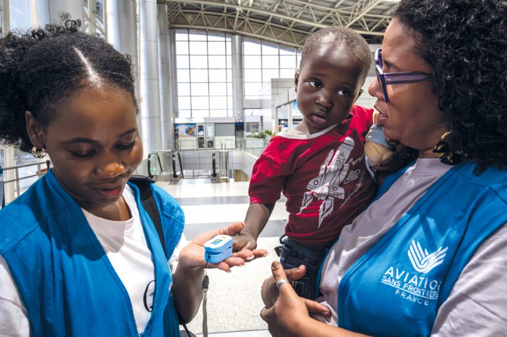 In the hustle and bustle of the airport, Amandine tenderly watches over a child awaiting departure, while a quick check validates his ability to travel.