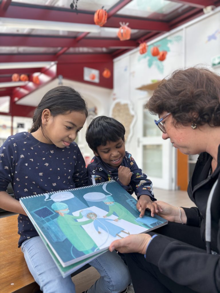 À l’aide d’un livre illustré, Murielle, éducatrice, prend le temps d’expliquer à Estelle et Kevin ce qui les attendra pendant leur séjour à l’hôpital.