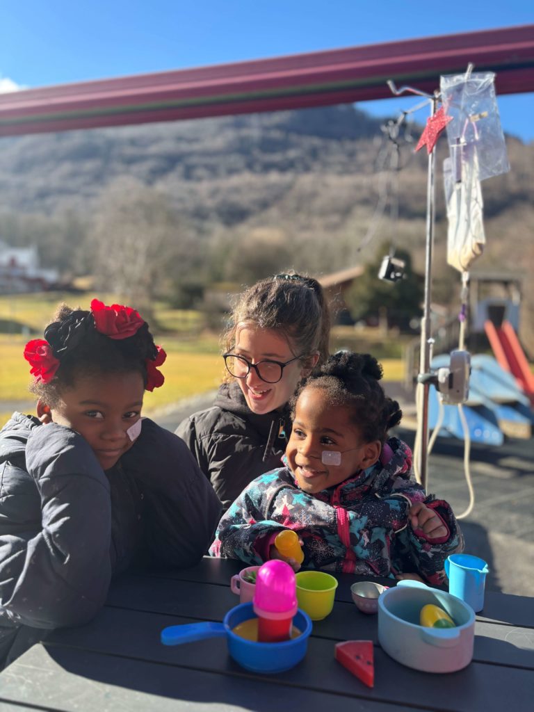 Aux côtés d’Eloïse, éducatrice, Eni-Ola et Oluyomi profitent du soleil hivernal en jouant.